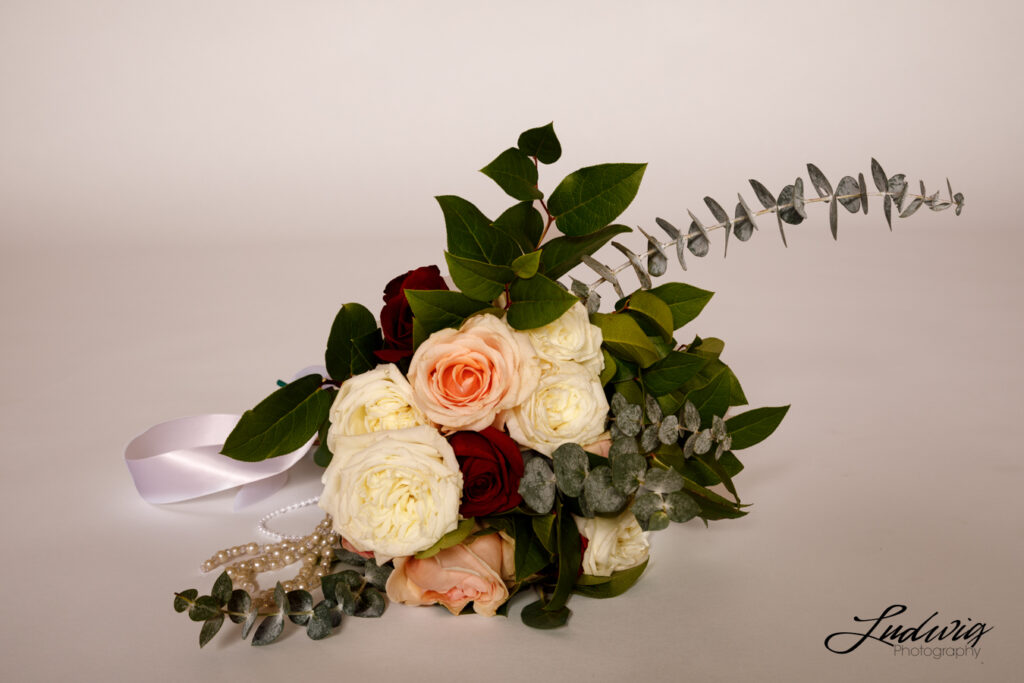 an image of a bouquet of white, pink and red roses with eucalyptus against a white background