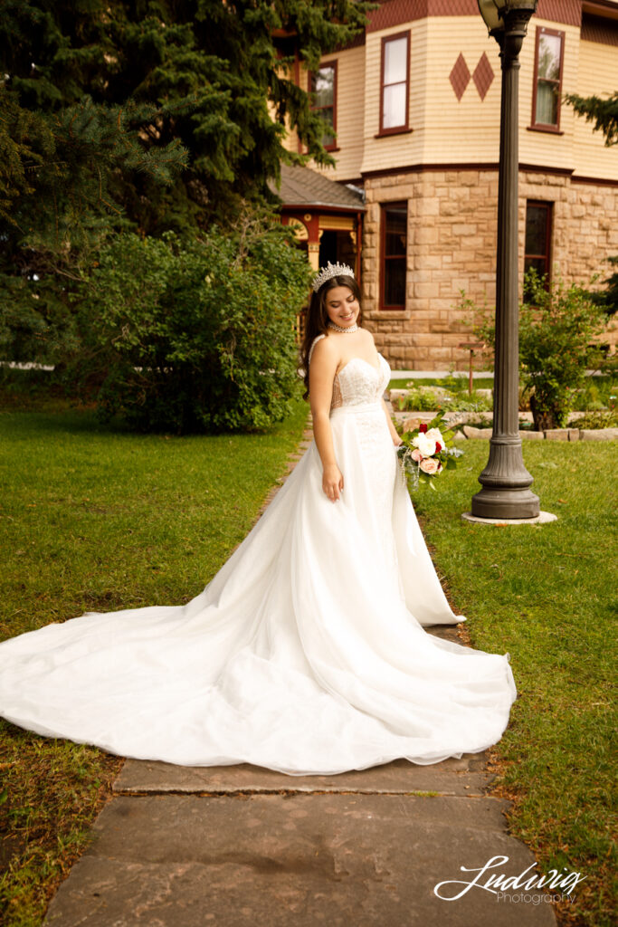 an outdoor portrait of a brunette bride in a wedding gown with the Historic Ivinson Mansion in the background