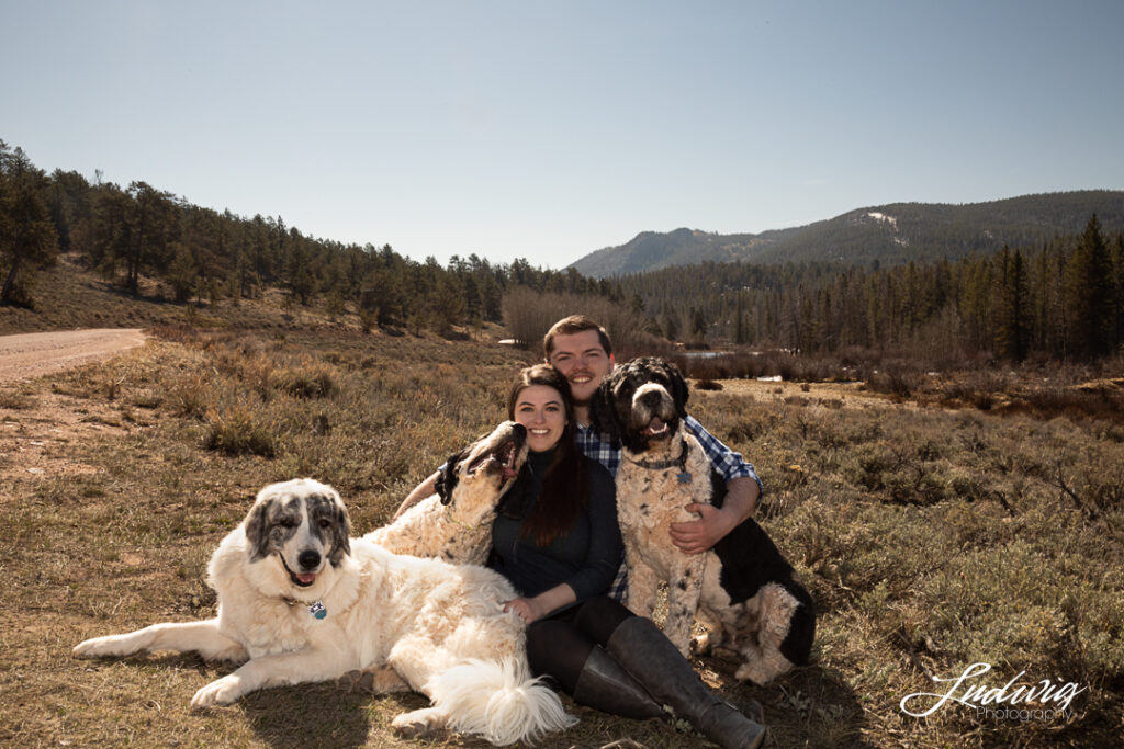 A couple sits outdoors Pilot Hill Laramie Wyoming with their three big dogs