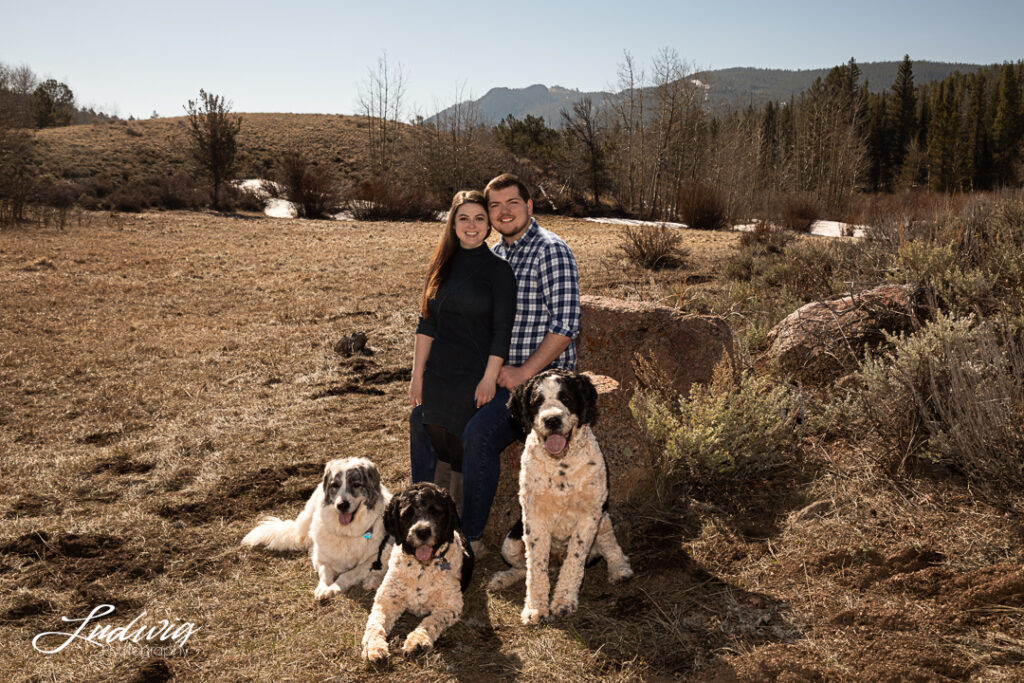 image of a couple smiling with their three dogs outdoors at Pilot Hill in Wyoming