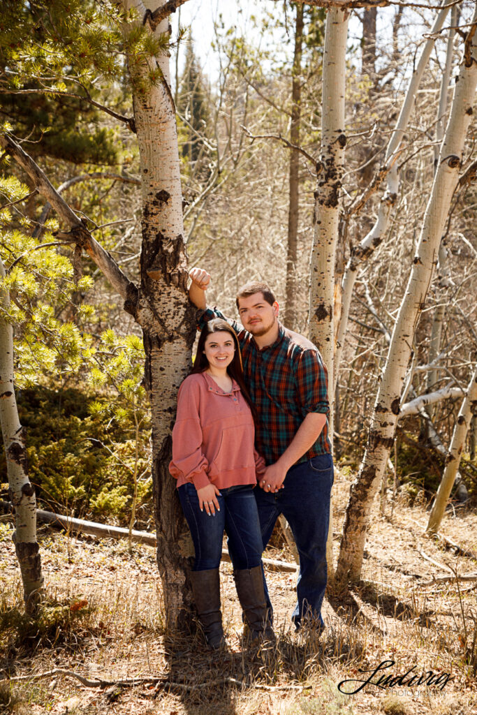 a young couple smiling at the camera in an aspen forest in Wyoming