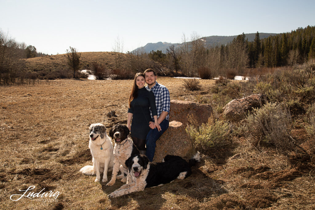 image of a couple smiling with their three dogs outdoors at Pilot Hill in Wyoming