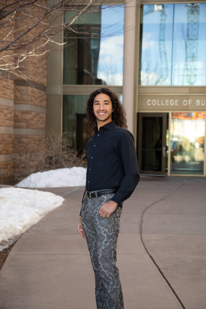 a young man poses for the camera in front of the college of business university of wyoming laramie. senior and professional photography photographer