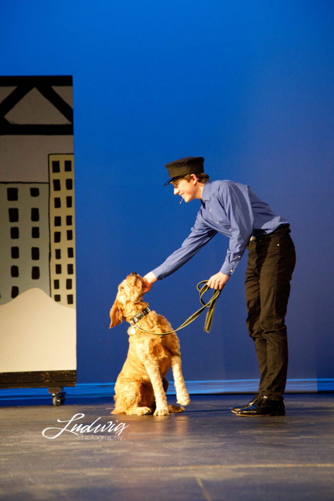 Sandy the dog standing with the police officer during Annie the Musical performed by Laramie High School Theatre