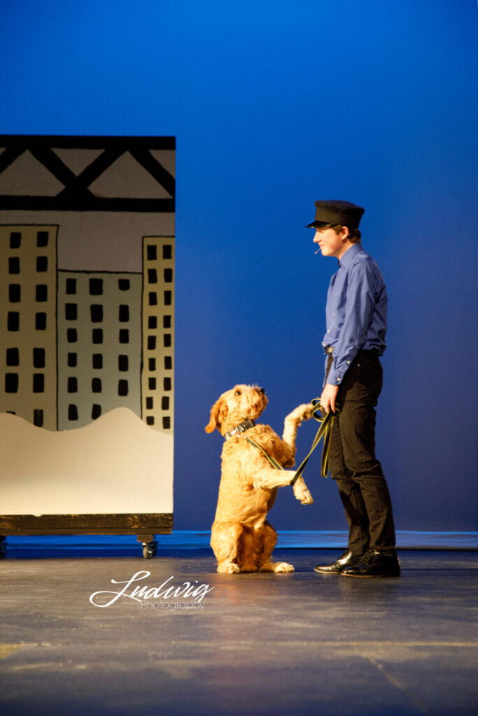 Sandy the dog standing with the police officer during Annie the Musical performed by Laramie High School Theatre