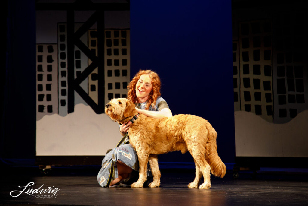 Girl singing to a dog in Annie