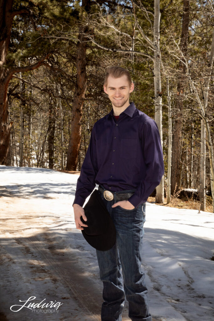 Portrait of a young man holding a cowboy hat, at Yellow Pine in Laramie Wyoming. Ludwig Photography